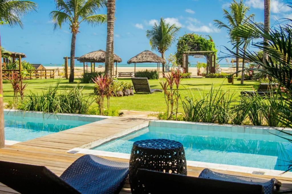 um resort com piscina, cadeiras e palmeiras em Pousada Mi Secreto em São Miguel do Gostoso