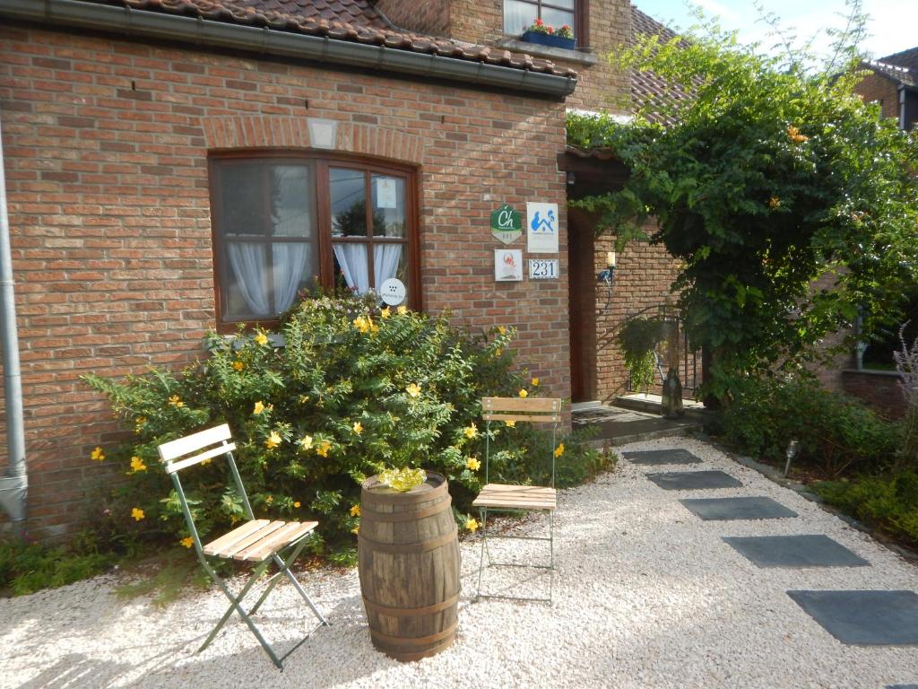 ein Gebäude mit zwei Stühlen, einem Fass und einem Baum in der Unterkunft B&B La Chrysalide in Mons