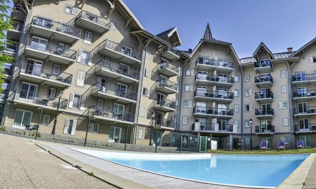 an apartment building with a swimming pool in front of it at Le Grand Panorama 5 Étage Terrasse Vue sur La Montagne in Saint-Gervais-les-Bains