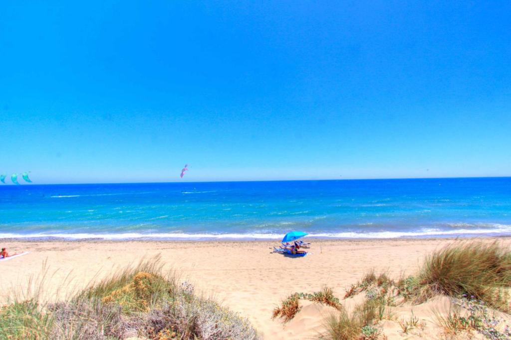einen Strand mit einem blauen Sonnenschirm und dem Meer in der Unterkunft 1176 beach front 2 pools bahia in Marbella