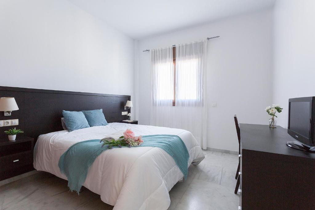 a bedroom with a bed and a desk and a television at Ático Lux Sevilla Nuevo Bormujos in Bormujos