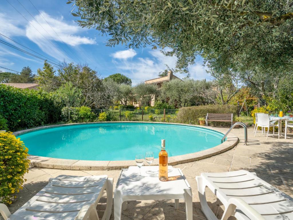 a pool with a table and chairs and a bottle of beer at Villa Chemin de la Plaine by Interhome in Peymeinade