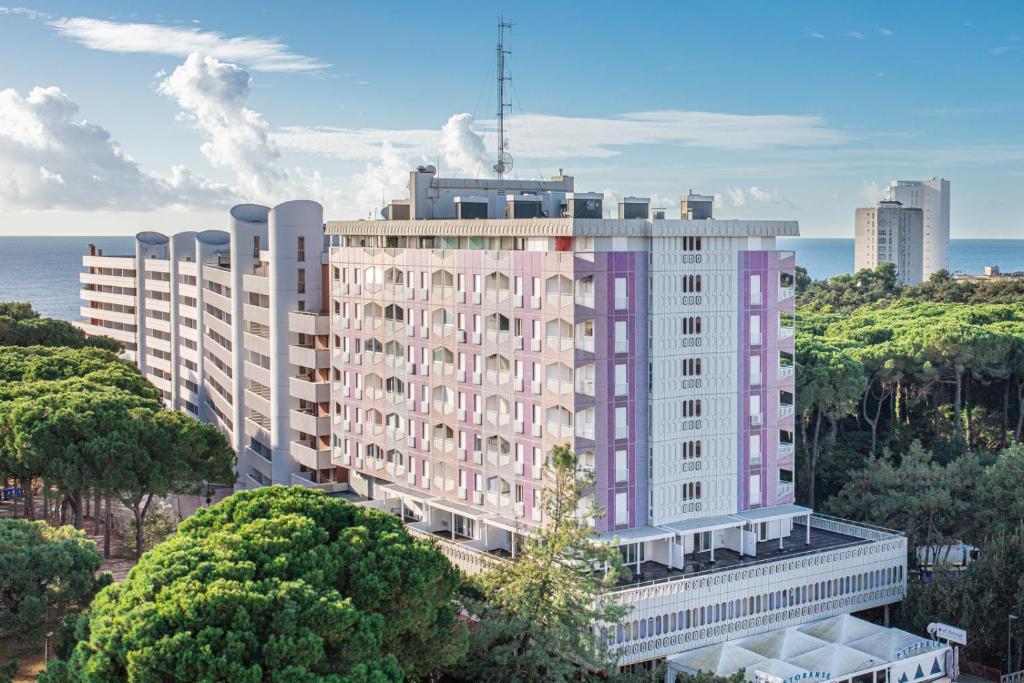 una rappresentazione di un grande edificio bianco con accenti viola di Hotel Regina a Lignano Sabbiadoro