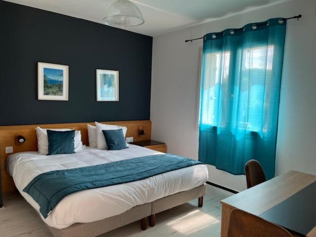 a bedroom with a large bed with a blue curtain at Appart'Hotel Festival Sud Suites - Avignon TGV in Avignon