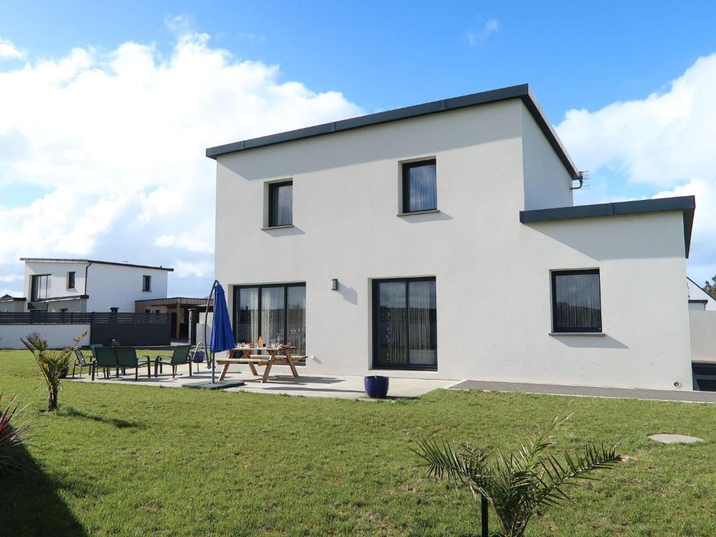 une maison blanche avec une table de pique-nique dans une cour dans l'établissement Holiday Home Les Agapanthes by Interhome, à Cléder