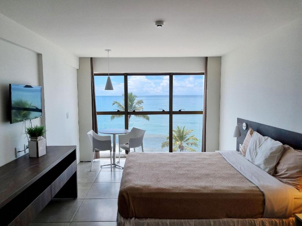 a bedroom with a bed and a view of the ocean at Flat Frente Mar + Limpeza | R601 in Maceió