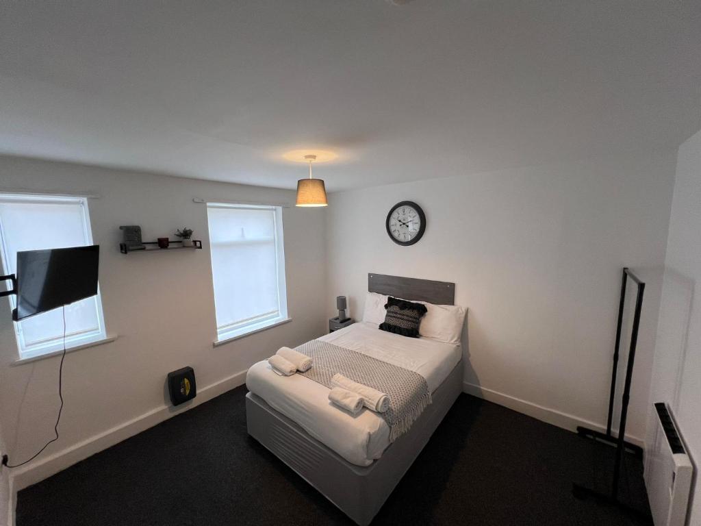 um quarto com uma cama e um relógio na parede em Harbour Flats em Skegness