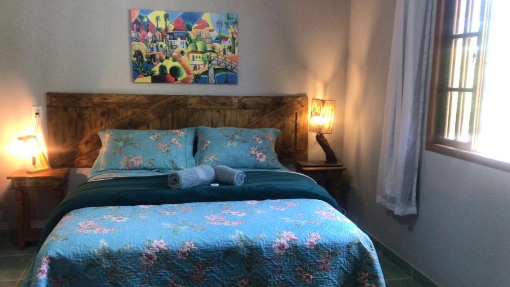 a bedroom with a bed with a blue comforter at Sítio por do Sol - Pedra Azul - ES in Pedra Azul