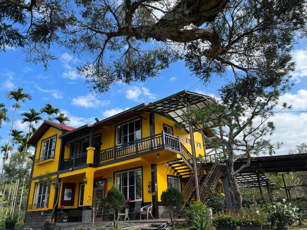 魚池鄉的住宿－清平樂村居，带阳台和树的黄色房子