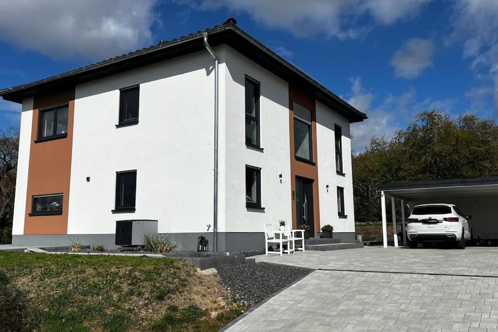 un edificio bianco con un'auto parcheggiata in un parcheggio di Familientraum a Großweitzschen