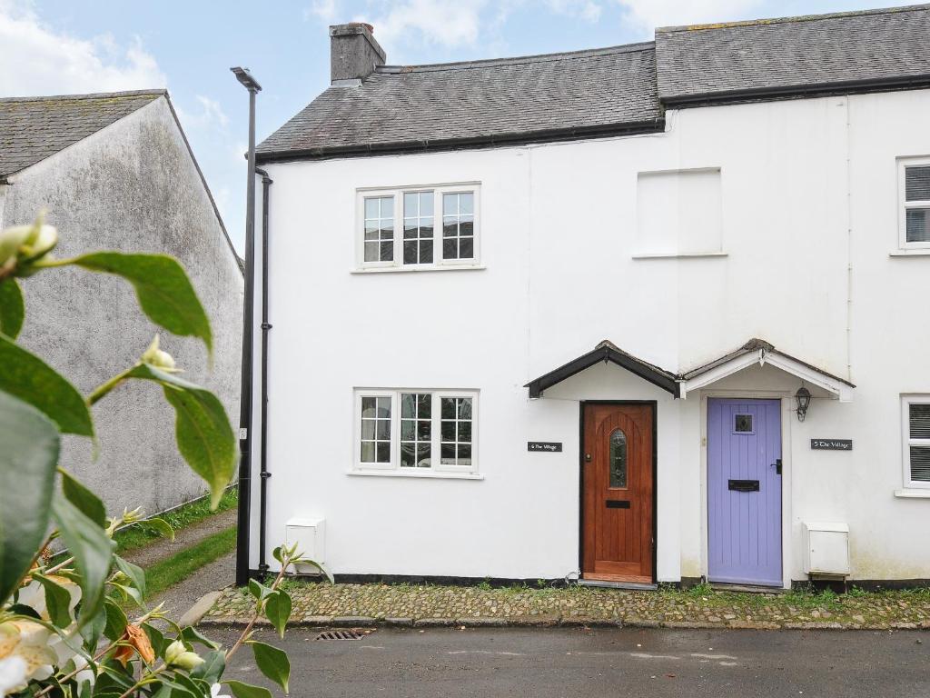 une maison blanche avec une porte violette dans l'établissement Glebe Cottage, à Yelverton