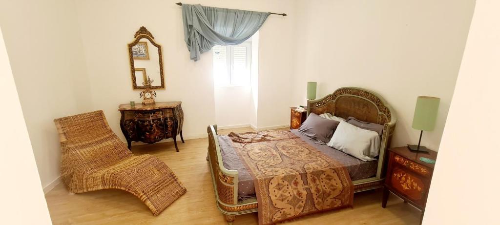 1 dormitorio con cama, silla y espejo en Beautiful Casita "12min from Torres Vedras", 