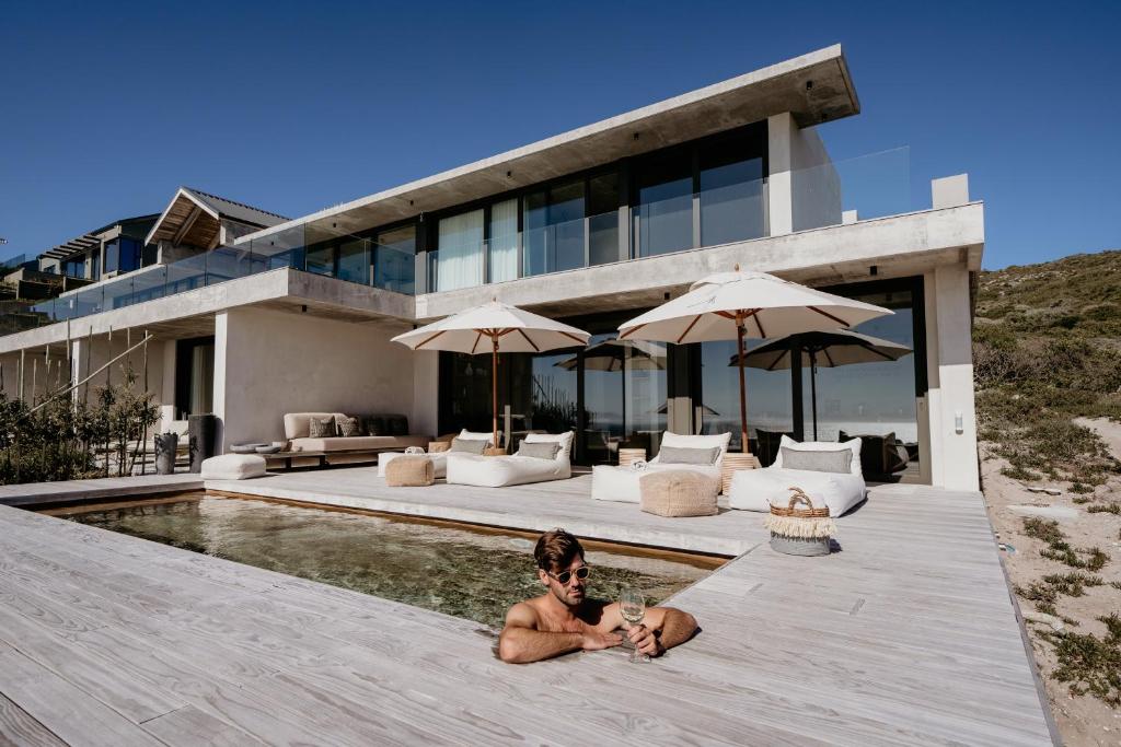 un uomo sdraiato nella piscina di una casa di Pure Sea Boutique Lodge a Gansbaai
