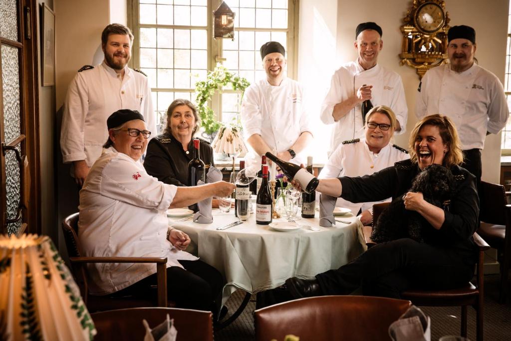 um grupo de pessoas em pé em torno de uma mesa com garrafas de vinho em Värdshuset Lindgården em Visby