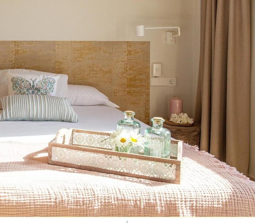 Una cama con una bandeja de vidrio con flores. en Hotel El Teular en Sueca