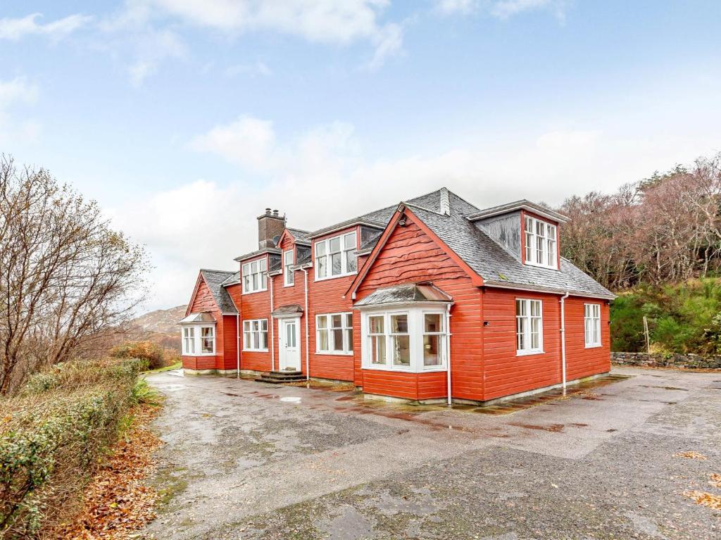 a red house with white windows in a driveway at 6 Bed in Lairg CA210 