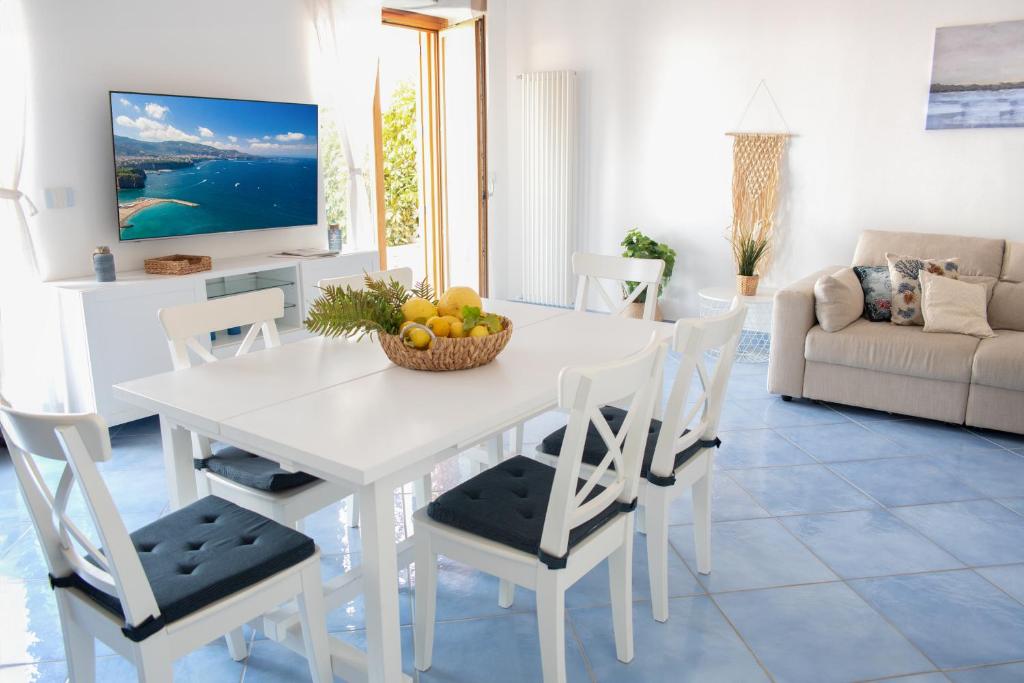 - une table à manger blanche avec des chaises et un bol de fruits dans l'établissement Fountain House Sorrento, à Sant'Agnello