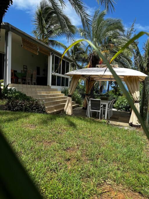 een huis met een veranda met een tafel en een paraplu bij Villa Karo Coco in Saint-Leu