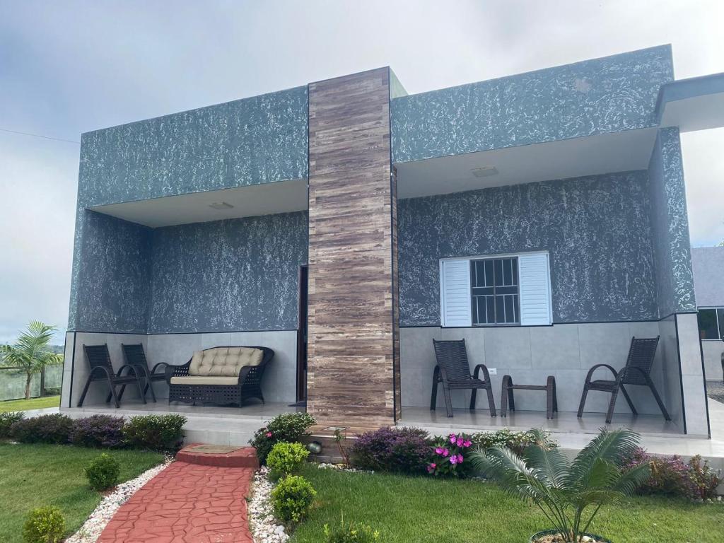 ein Haus mit Stühlen und einer Couch auf einer Terrasse in der Unterkunft Chácara Recanto das Aves in Pilar do Sul