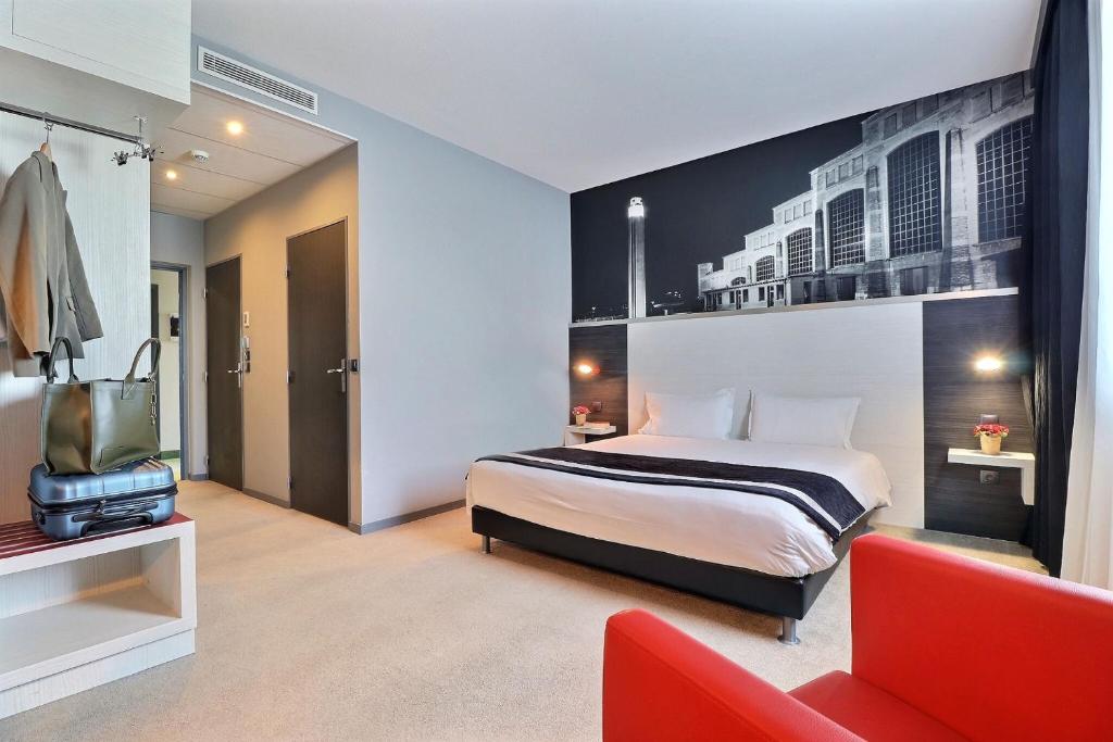 a hotel room with a bed and a red chair at Hôtel des Lumières Lyon Meyzieu Arena Stadium in Meyzieu