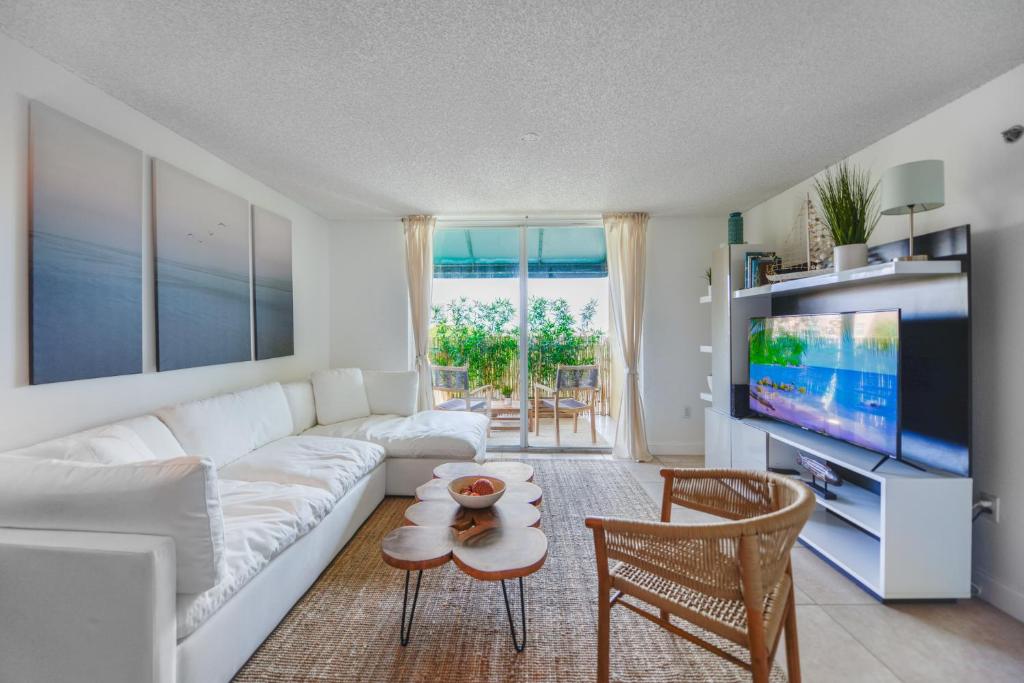 Lux Condo at Yacht Club 10 min from Beach في ميامي: غرفة معيشة مع أريكة بيضاء وتلفزيون