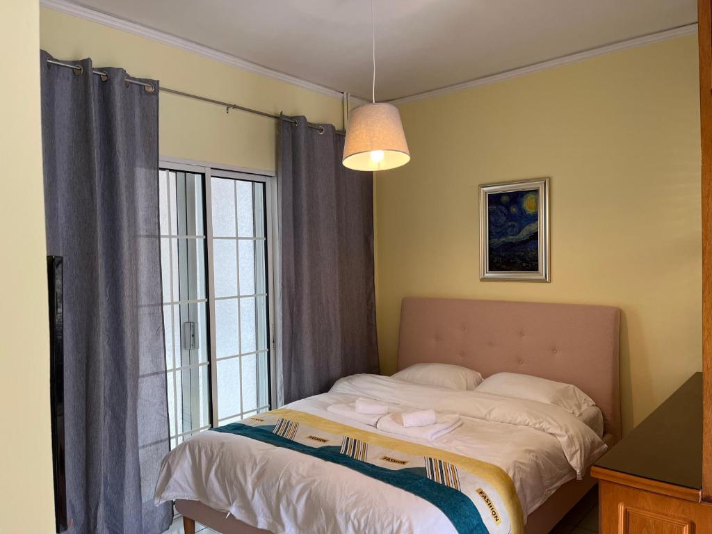 a bedroom with a bed and a large window at Qqueen House in Piraeus