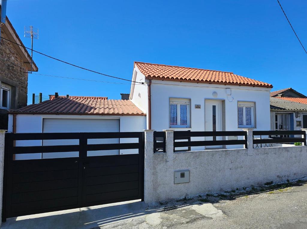 a white house with a black gate and a fence at Casa de Lupa - Camariñas - Costa da Morte in A Coruña