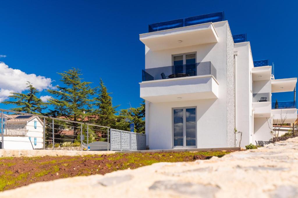 Cette maison blanche dispose d'un balcon sur la plage. dans l'établissement Apartment Mialis, à Krk