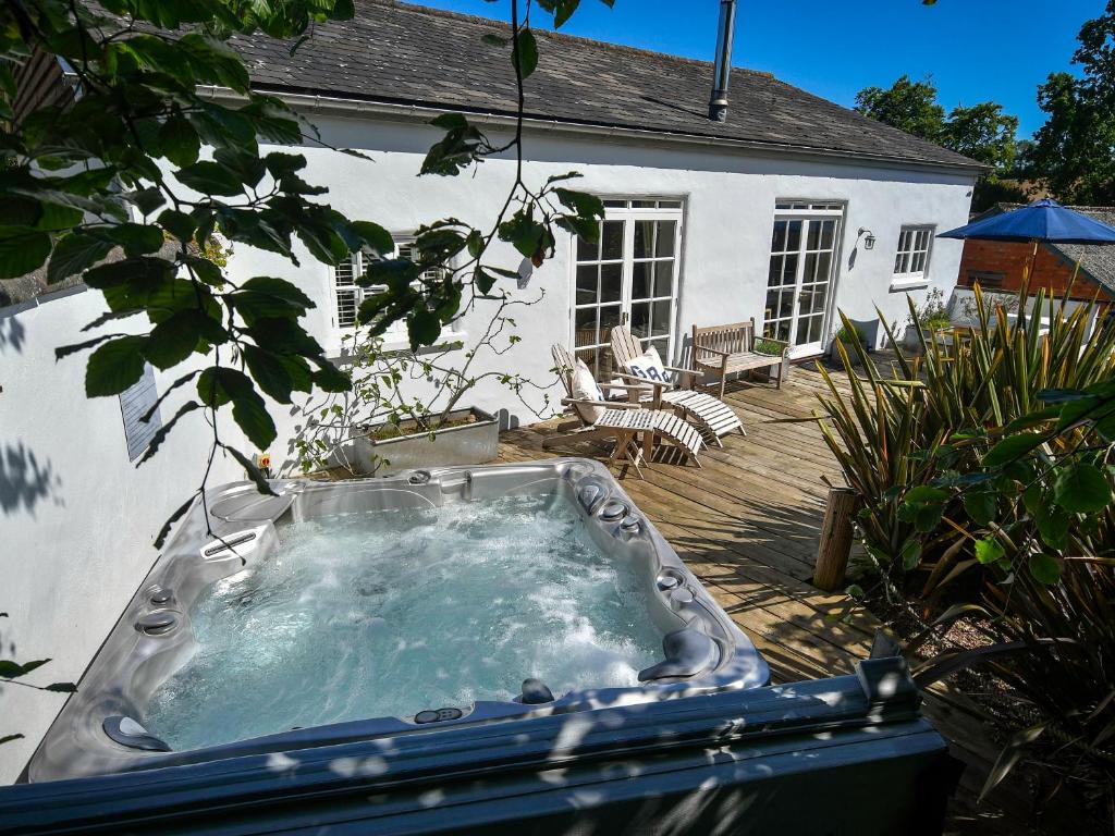 a hot tub on a deck in front of a house at Burrows in Venn Ottery