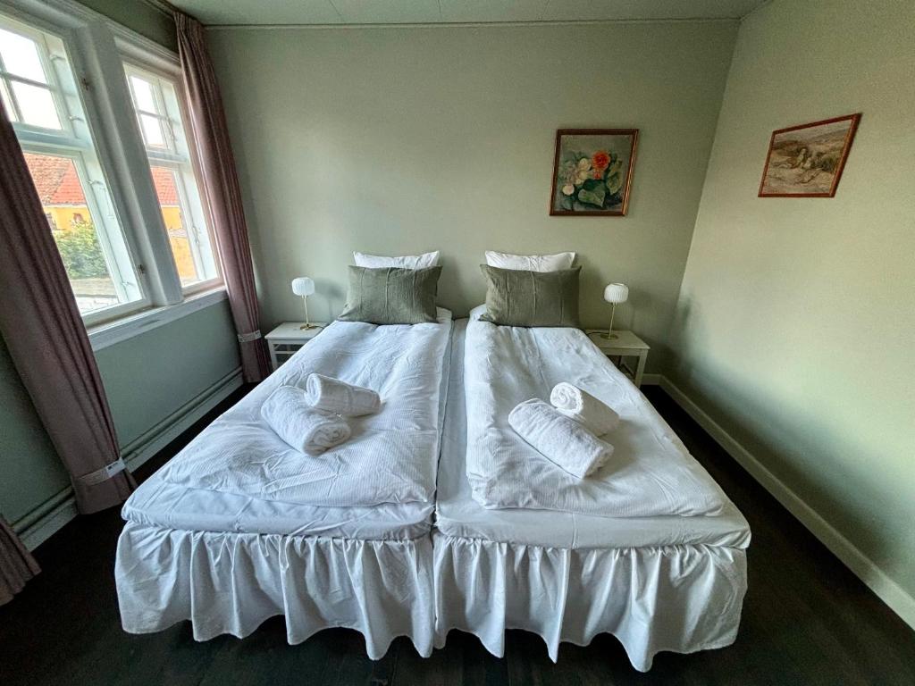 Schlafzimmer mit einem Bett mit weißer Bettwäsche und Kissen in der Unterkunft Hotel Kysten in Hasle