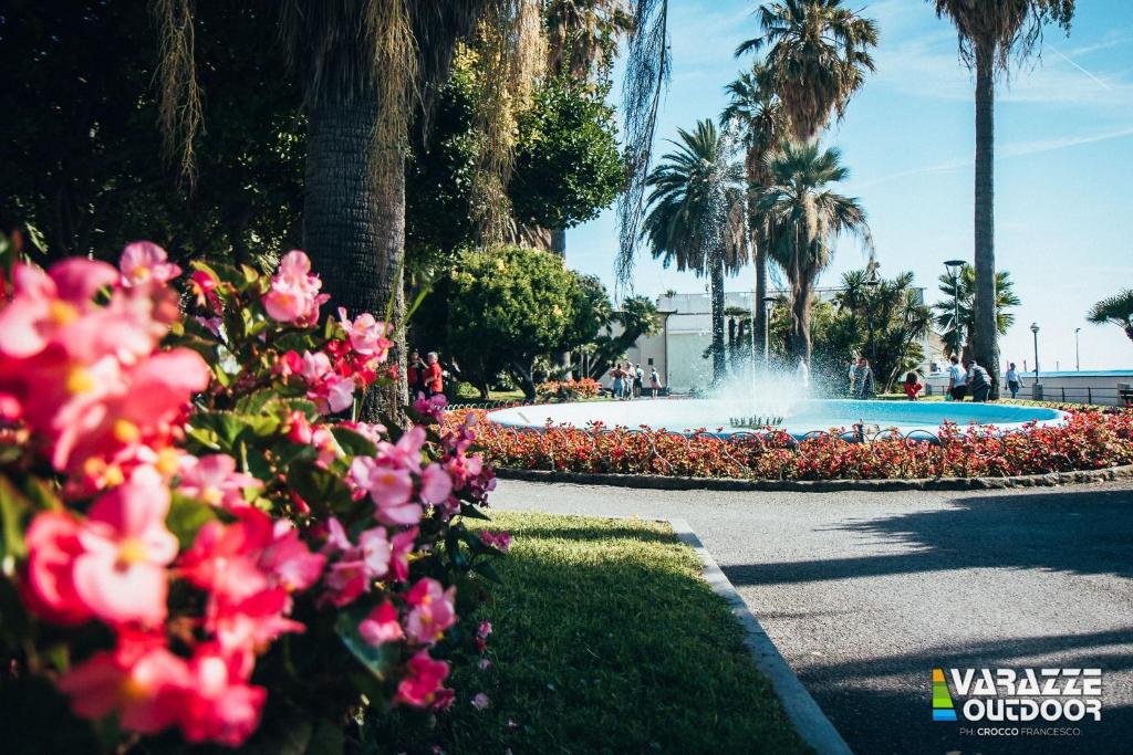 a fountain in a park with pink flowers and palm trees at Blackstone Apartment in Varazze