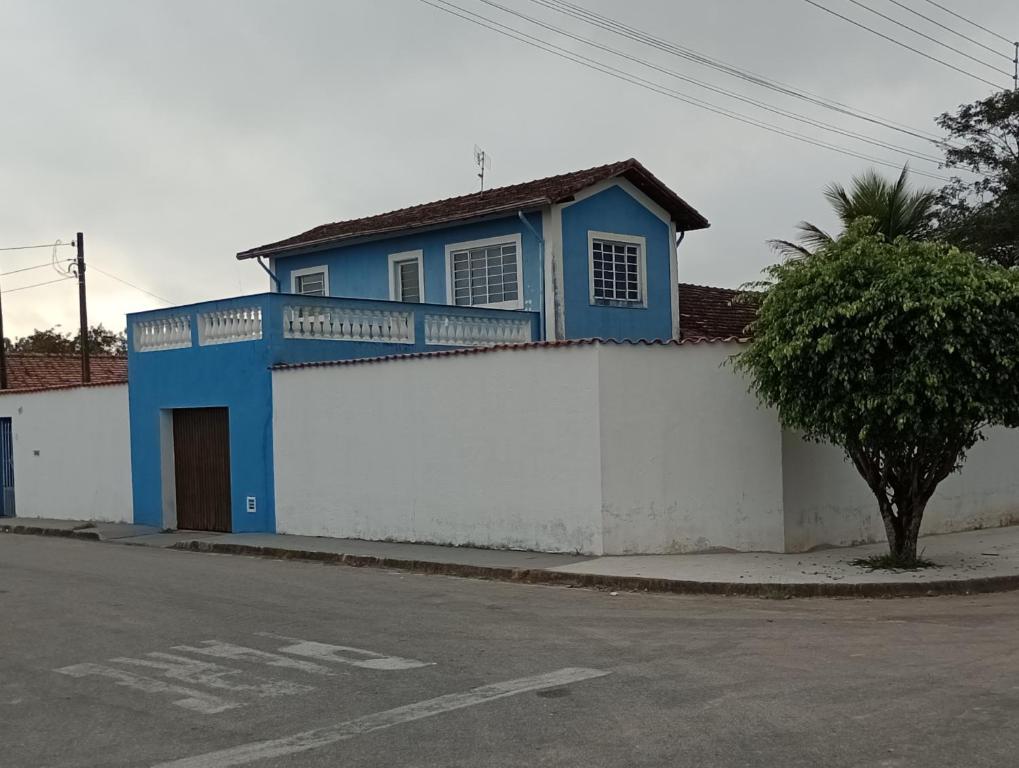 un edificio blu e bianco con un albero accanto a una strada di Espaço temporada Gardenias Guaratinguetá Proximo Basilica de Aparecida a Guaratinguetá