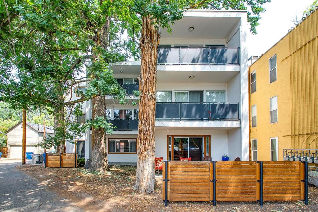 Un edificio de apartamentos con una valla de madera delante de dos árboles. en Ninth Street Retreat, en Boise