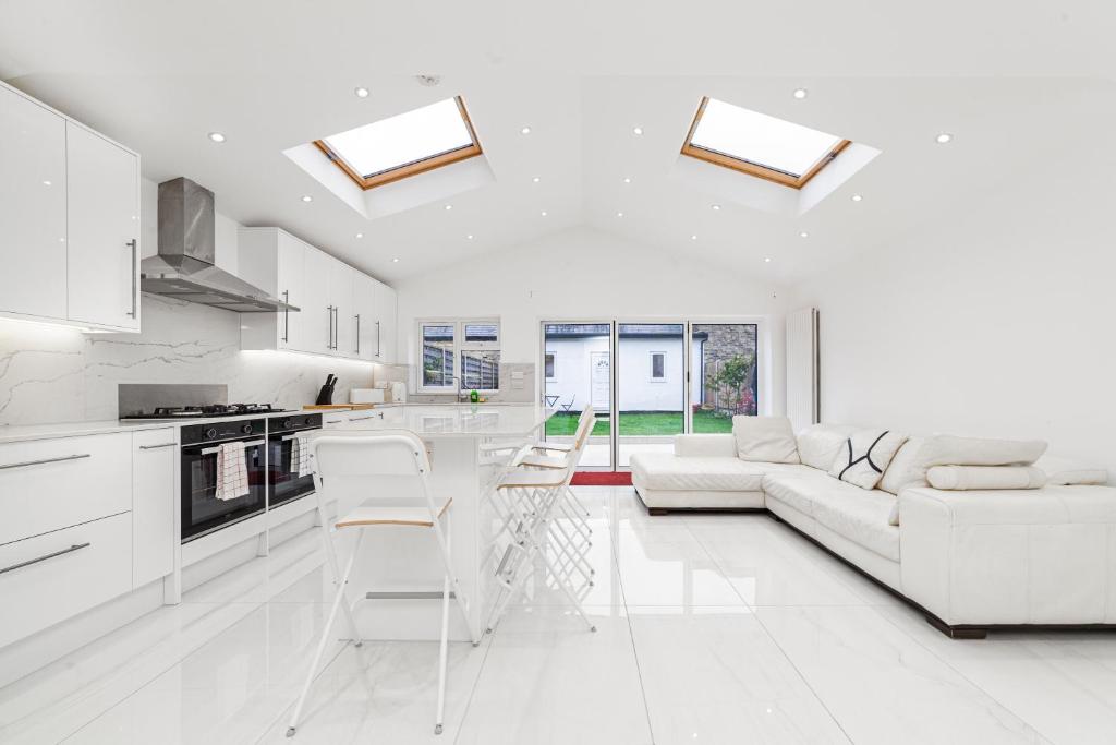 ein weißes Wohnzimmer mit einem Sofa und einer Küche in der Unterkunft Spot Homes Guest House in London