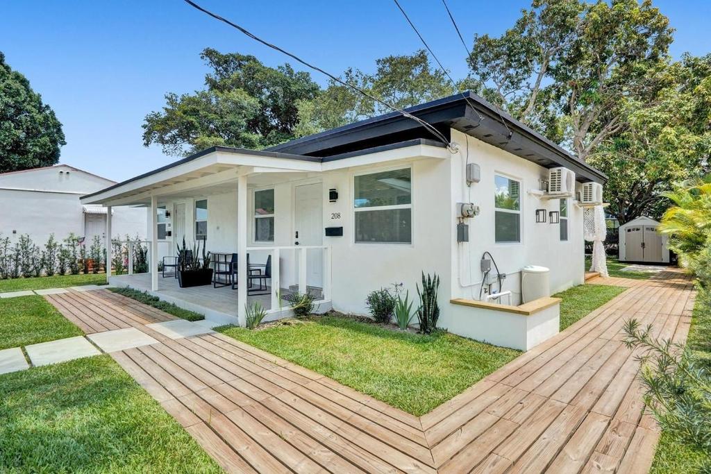 a small white house with a wooden deck at Hallandale Beach Family Vacation Home Backyard in Hallandale Beach