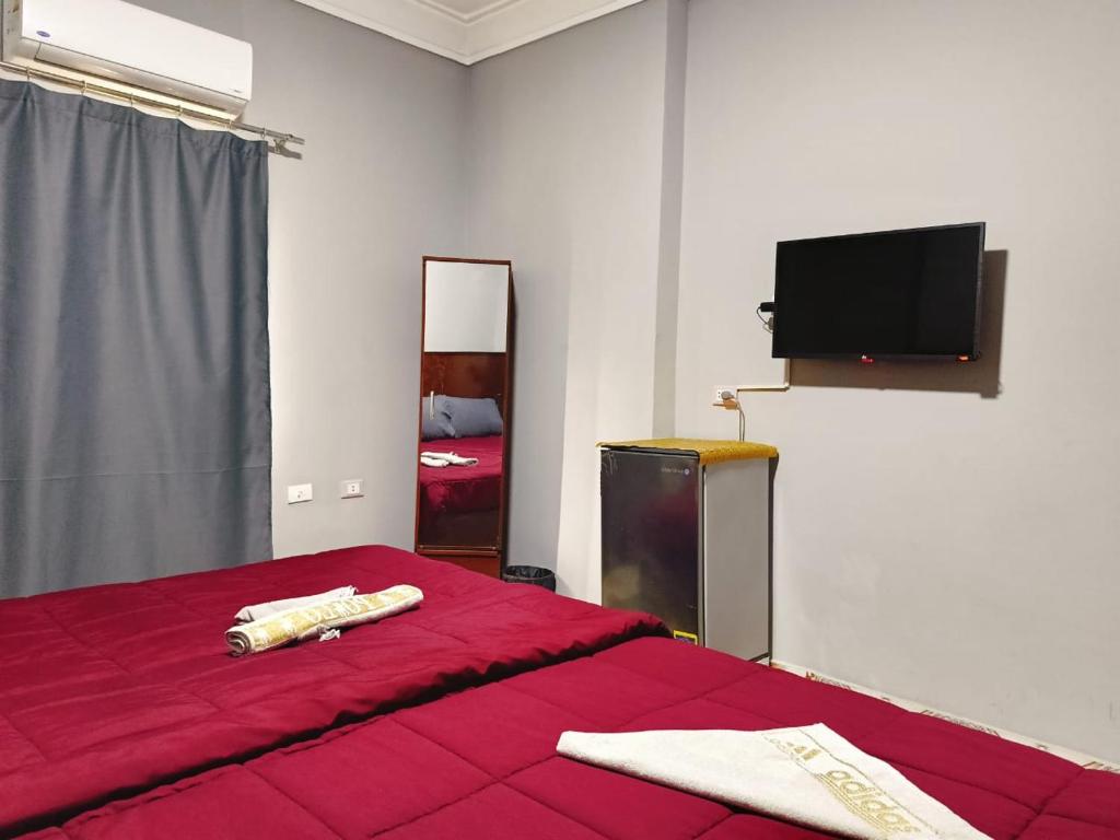 a bedroom with a red bed and a flat screen tv at fantastic nine pyramids in Cairo