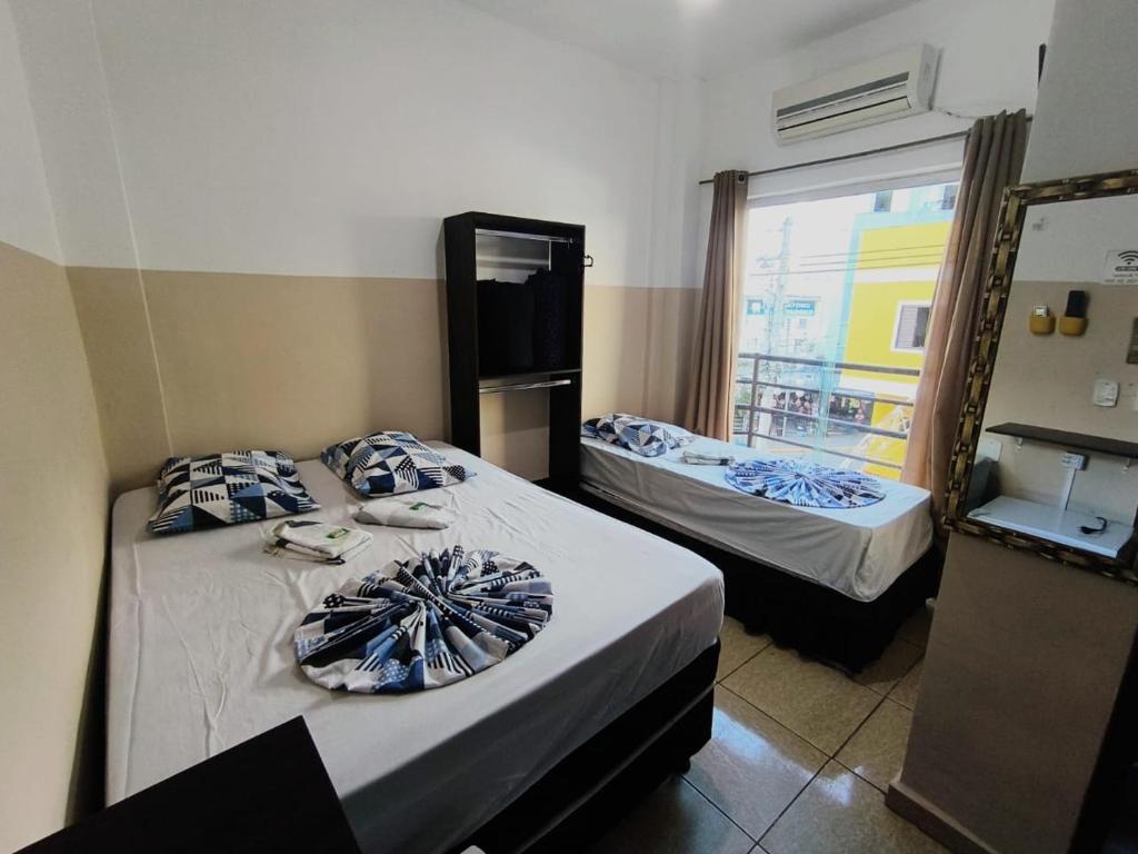 two beds in a room with a window at Hotel Mãe Rainha in Aparecida