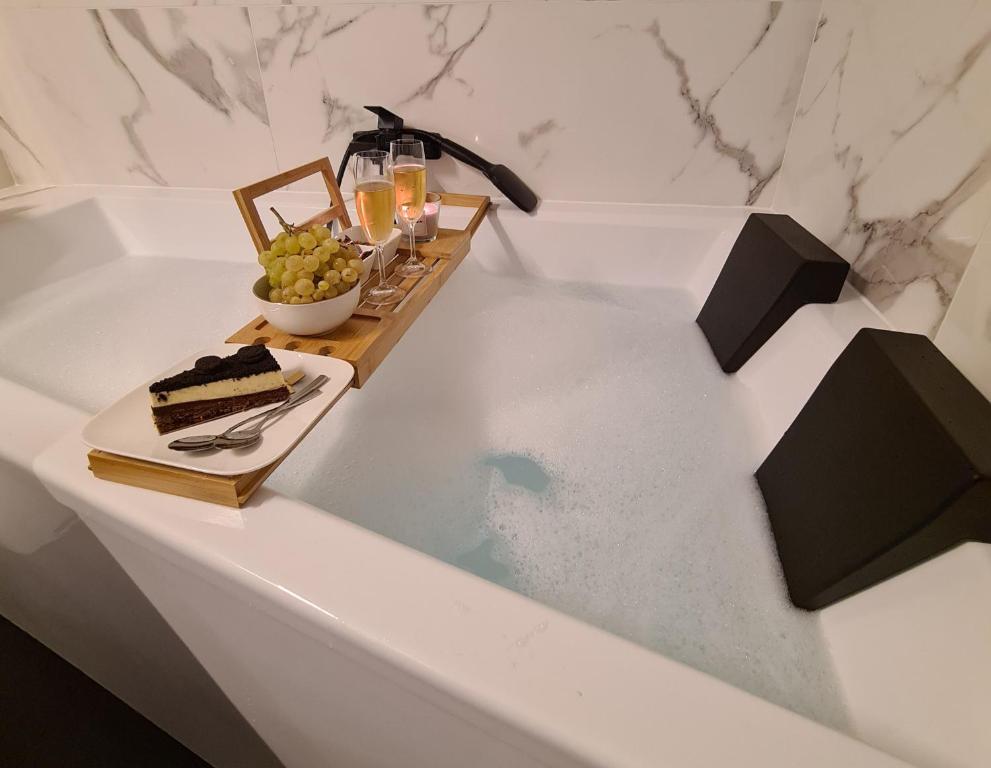 eine Badewanne mit einem Stück Kuchen und einem Teller Trauben in der Unterkunft Baignoire Spa - 2 pièces moderne in Villeneuve-la-Garenne