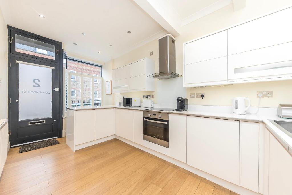 a kitchen with white cabinets and a large window at Stylish & spacious 3 bed Victorian house sleeps up to 7 - near O2, Museums, Excel, Mazehill station 12 mins direct into London Bridge in London