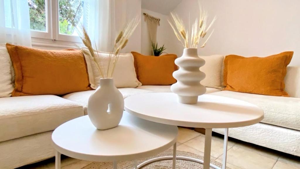 zwei weiße Vasen auf Tischen im Wohnzimmer in der Unterkunft Villa Jenny Stylianou in Spetses