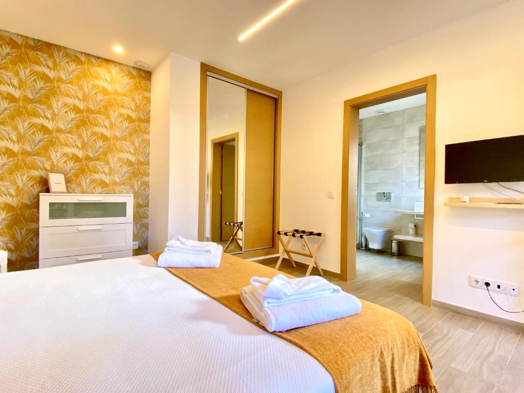a bedroom with a large white bed with a tv at Quinta das Andorinhas in Carvoeiro