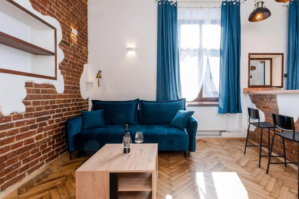 ein Wohnzimmer mit einem blauen Sofa und einer Ziegelwand in der Unterkunft Charming central apartment in Krakau
