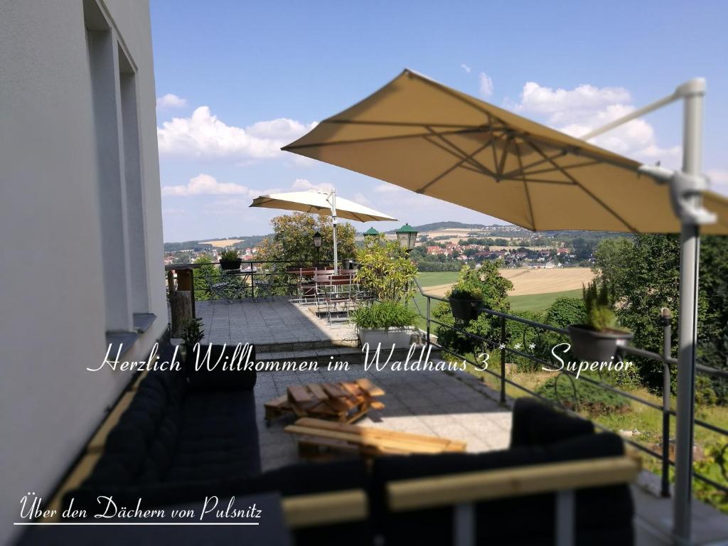 a patio with an umbrella and a table at Waldhaus Pulsnitz in Pulsnitz