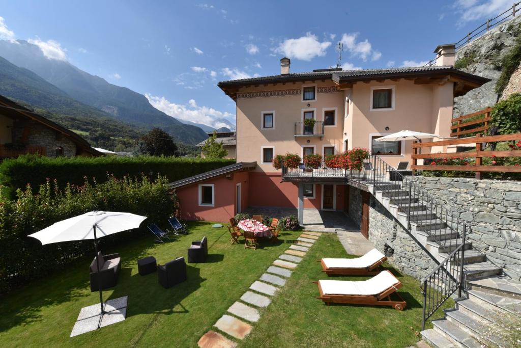 a house with a yard with chairs and an umbrella at Au Berceau du Bien-Etre in Chambave