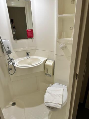 Baño blanco con lavabo y espejo en Fasthotel, en Jaux