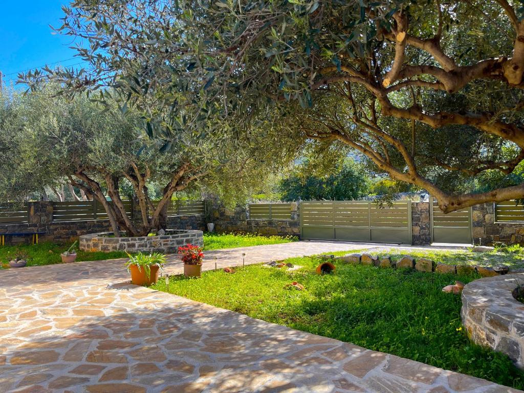 a garden with two trees and a stone walkway at Elounda Holidays Argyro in Elounda