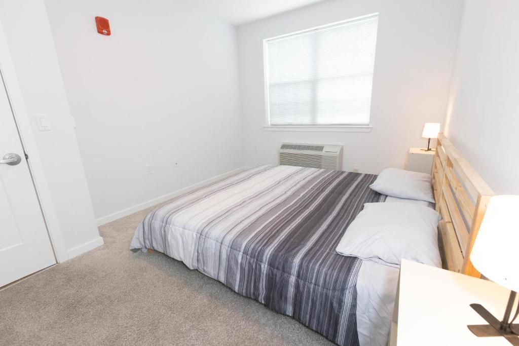um quarto branco com uma cama e uma janela em Modern & Cozy 2 - Bedroom gem mins from NYC em Jersey City