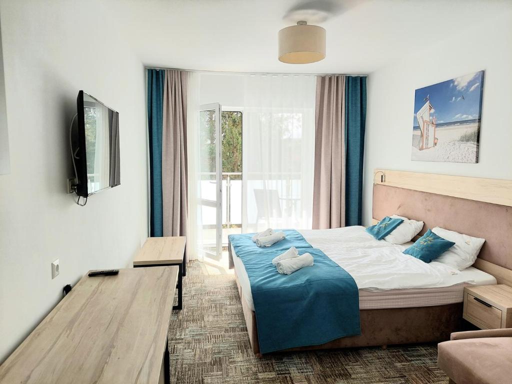 1 dormitorio con 1 cama con sábanas azules y TV en Apartament 106 Mari - Welle, en Grzybowo