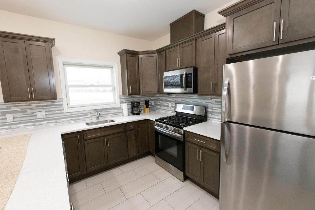 a kitchen with wooden cabinets and a stainless steel refrigerator at Elegant Modern 3-Bed Apt near NYC in Jersey City