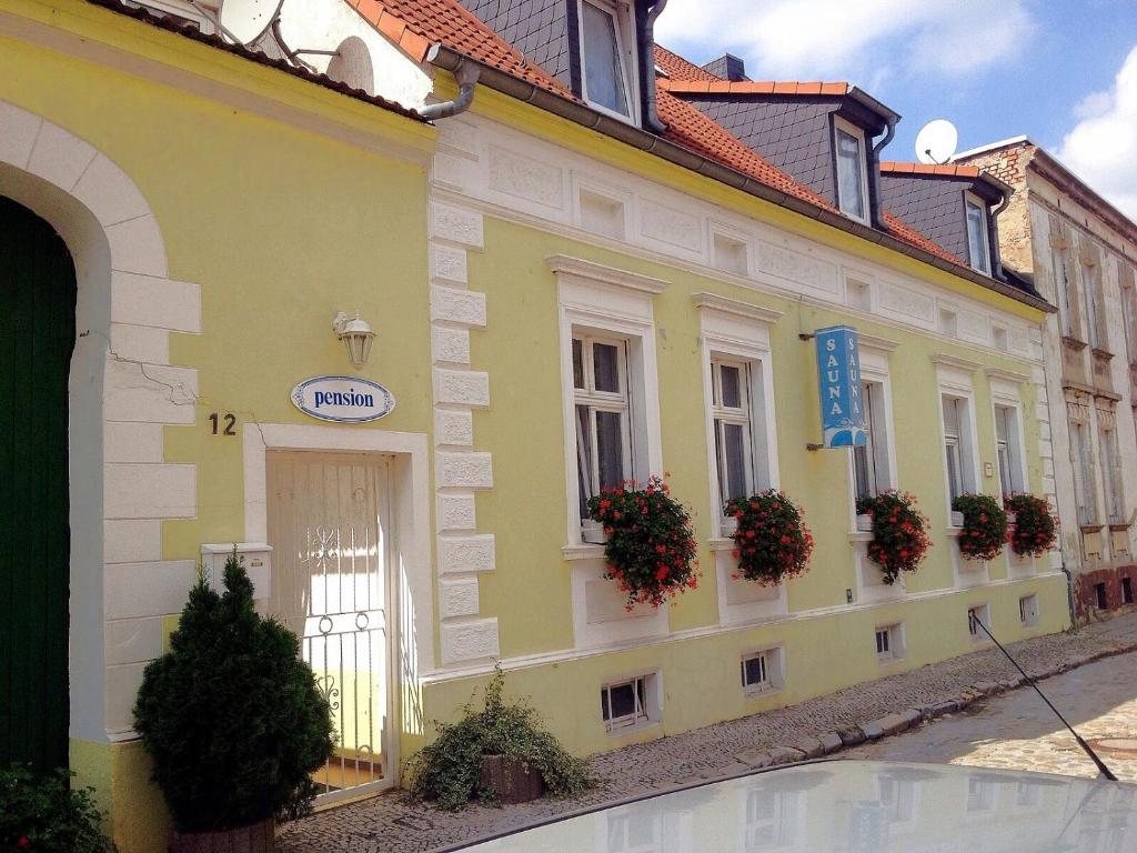 un edificio amarillo con macetas de flores a un lado. en pension & sauna AM LORENZ, en Calbe